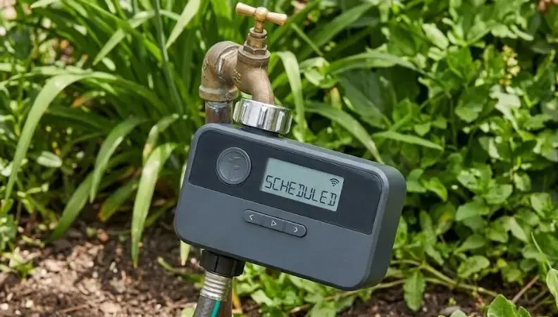 Programador de riego inteligente instalado en un grifo de jardín con adaptador metálico
